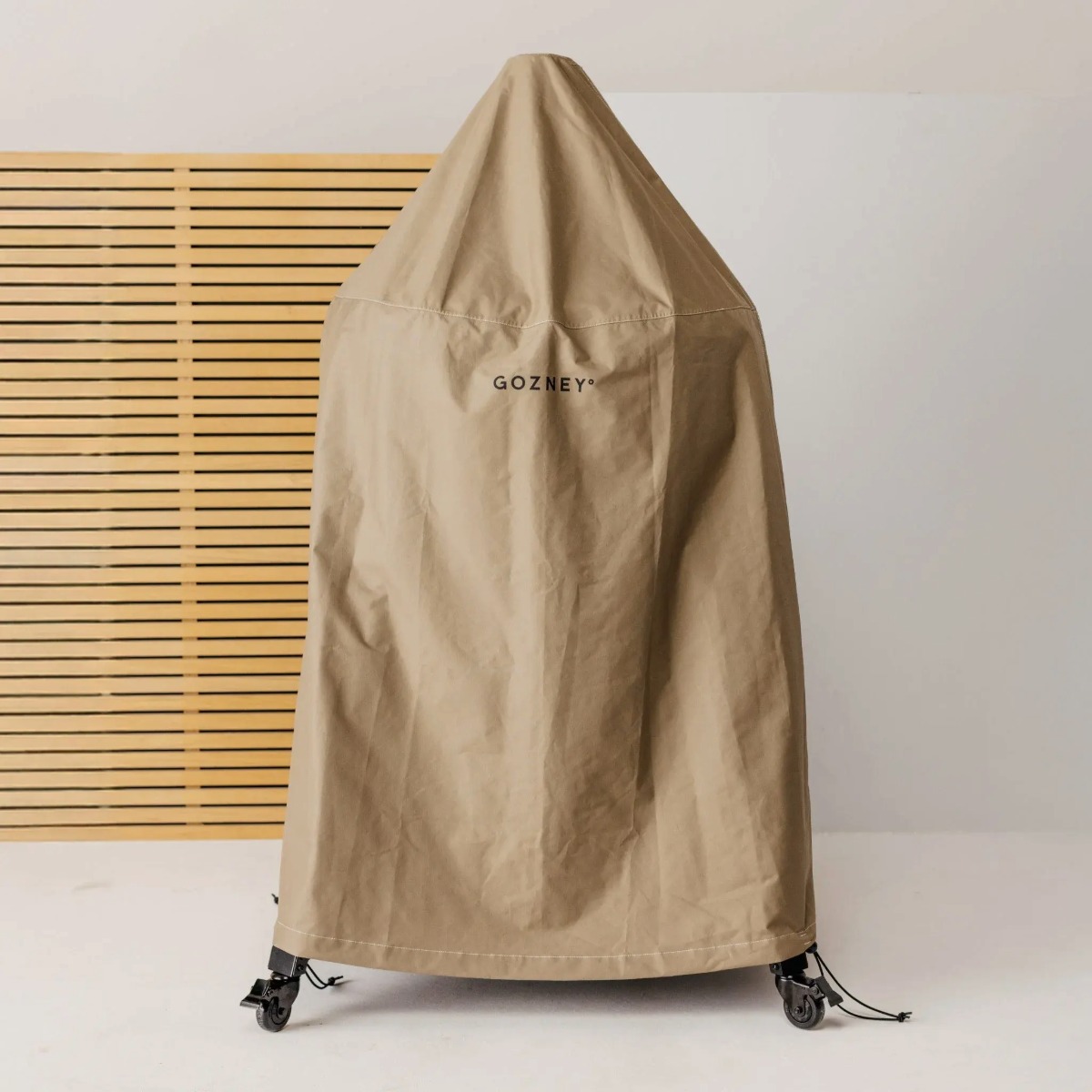 Gozney Dome Gen 2.0 Abdeckhaube Kurz  Beige Abdeckhaube vor Holz Hintergrund